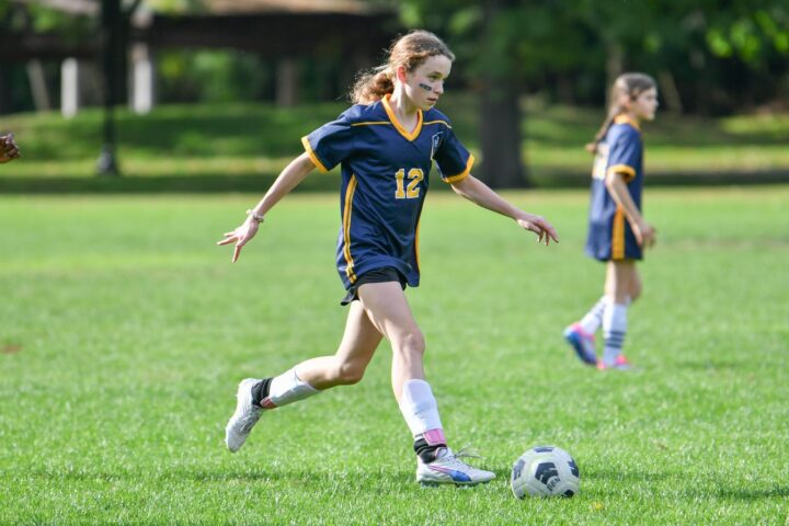 A girls soccer player dribbles the ball