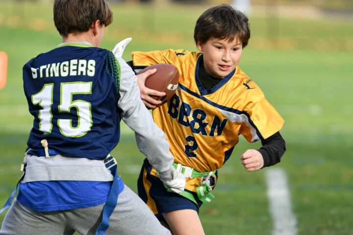 A flag football player runs around a defender