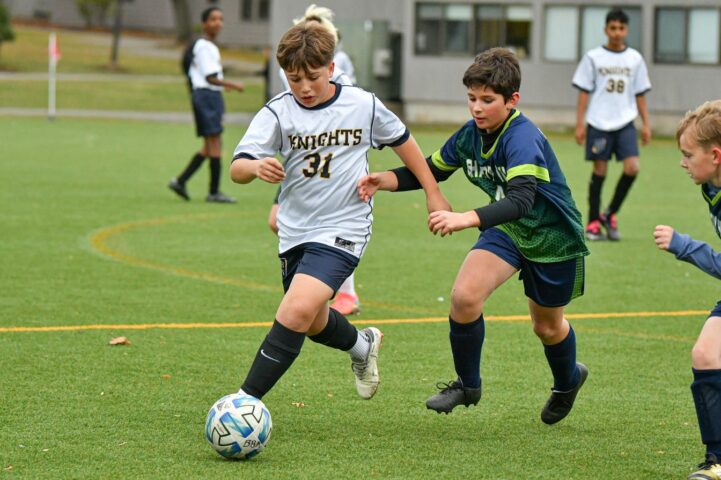 A boys soccer player dribbles past a defender