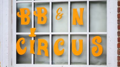 A window with yellow letters spelling "BB & N Circus" displayed on the glass panes.